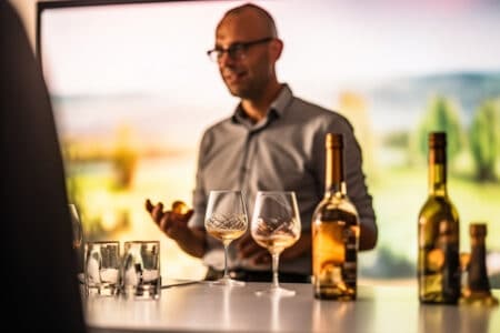 all images man standing behind table wine glasses bottle